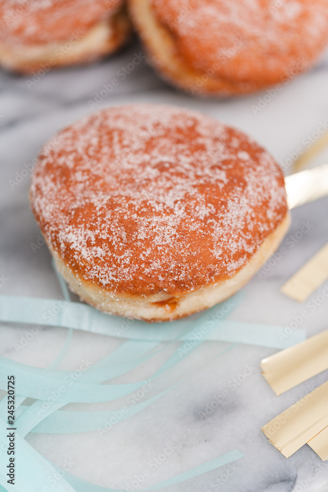 Traditional German or Austrian fried donuts with no hole, so called Krapfen, Berliner or Pfannkuchen with cinnamon sugar and filled with rose hip, raspberry or strawberry jam, party or carnival food