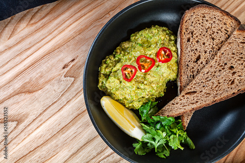 Top view on guacamole with hot pepper, lemon and bread. Mexican food snack. Flat lay food. ealthy food for menu. Free copy space. Healthy diet background. photo