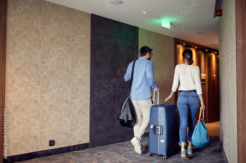 Couple arriving at hotel lobby with suitcase. photo