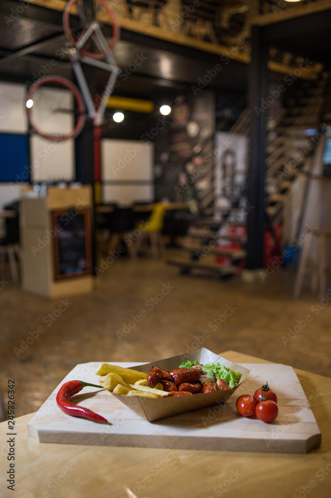 Sausages and french fries on a wooden board with fresh vegetables. Sausages and french fries on a wooden board with fresh vegetables.