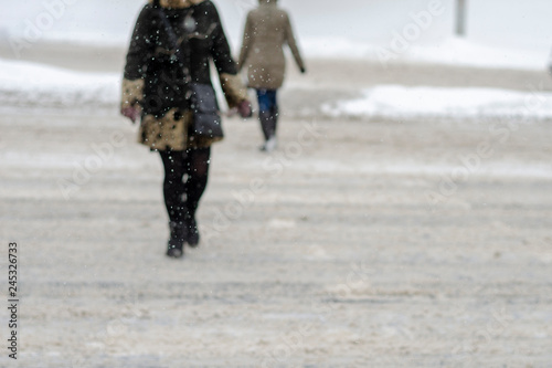 Blurred photo can be used as a background for the text. lonely grandmother, a woman walking on the street during snowfall, view from behind