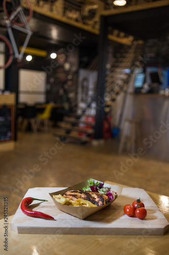 Grilled chicken breast with fries on a wooden board with fresh vegetables photo