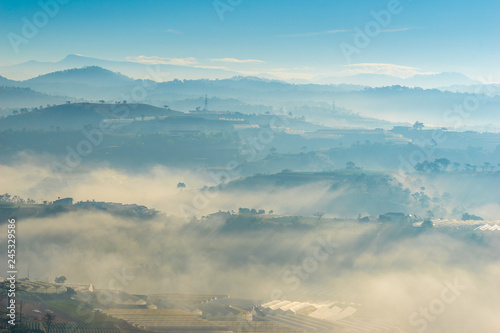 the fog and the sun in an early morning at Da Lat city, the pine hill and greenhouse under the hill in mist