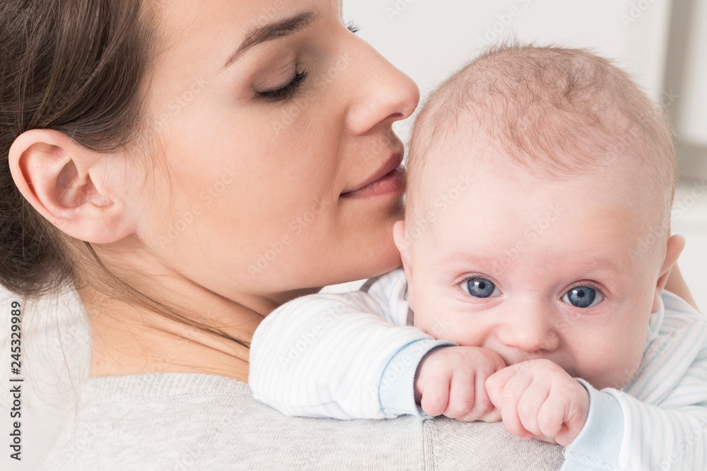 Beautiful young mother holding baby with big blue eyes Beautiful young mother holding baby with big blue eyes