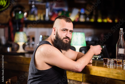Guy spend leisure in bar with alcohol. Man drunk sit alone in pub. Alcoholism and depression. Alcohol addicted concept. Hipster brutal man drinking alcohol ordering more drinks at bar counter