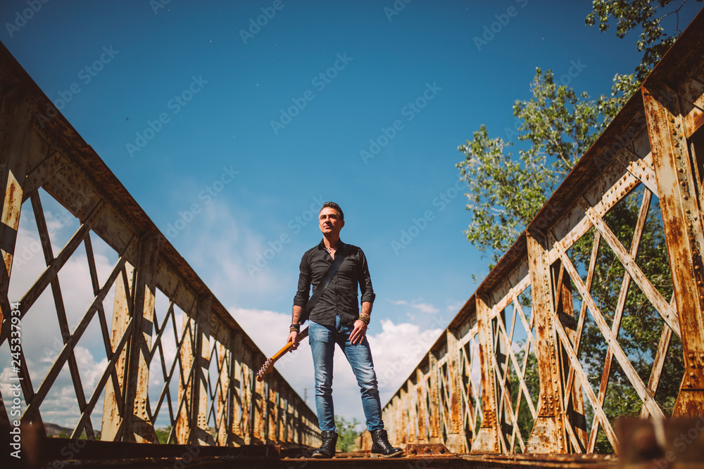 Man with guitar standing on bridge Man with guitar standing on bridge