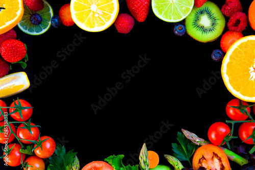 circular background with spring and summer colorful fruits and vegetables on black table from above with large copy space