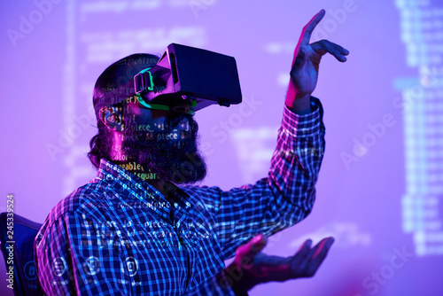 Electronic decoded data and contemporary it engineer in vr headset touching virtual display during resentation photo