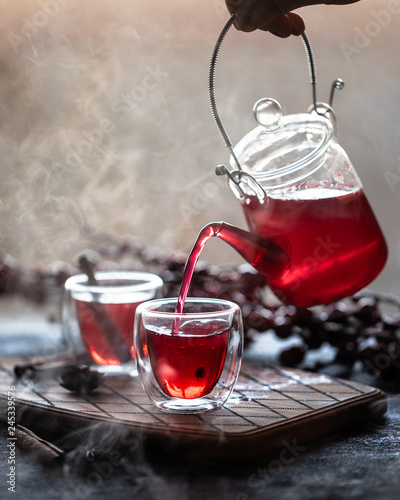 Process brewing tea, tea ceremony, cup of freshly brewed fruit and herbal tea. Hot water is poured from the kettle into a cup.