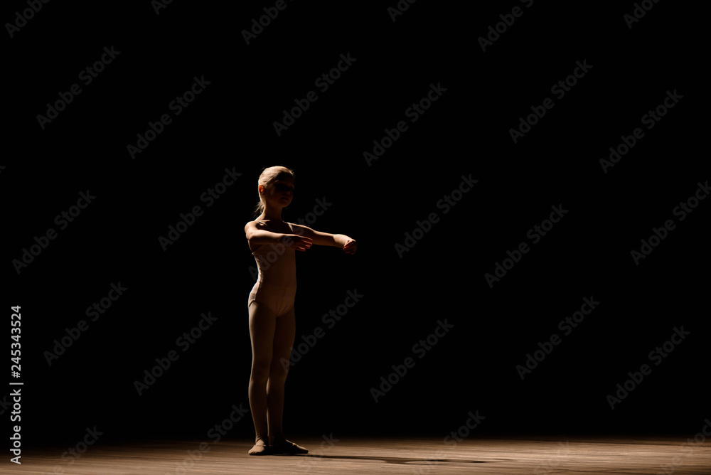 Very young ballerina posing on a black background