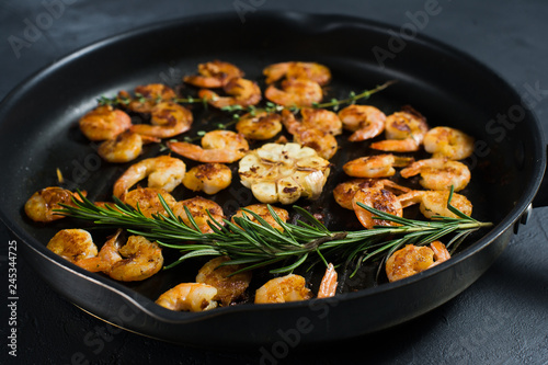 Fried shrimp in a frying pan, fried garlic, rosemary. Close-up.