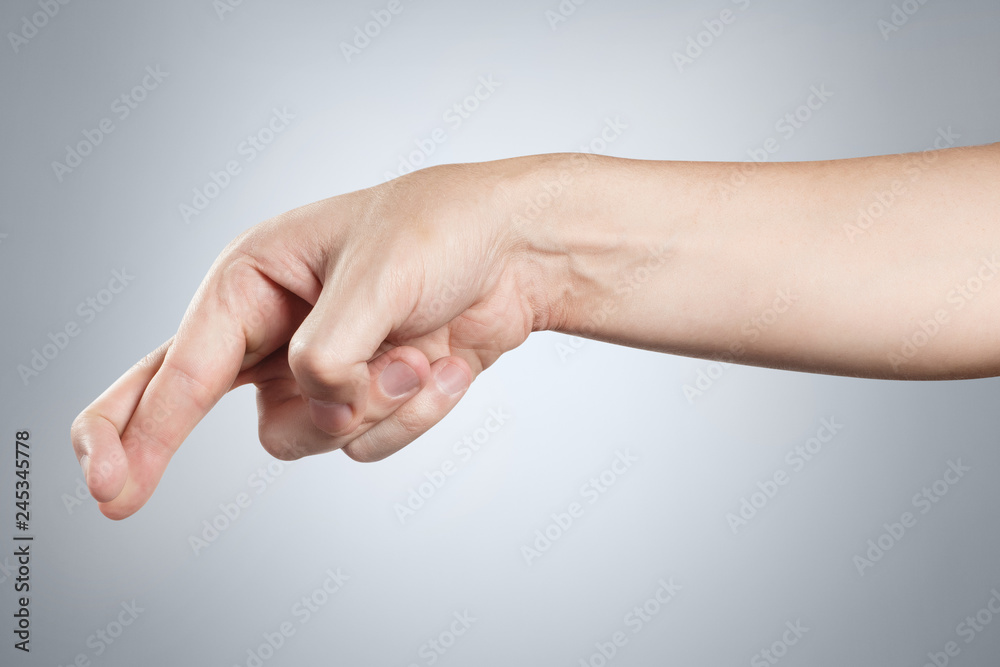 Hand showing cheating sign on gray background Hand showing cheating sign on gray background