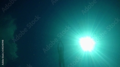 Free diver descending from surface to bottom of the lake in very clear and transparetn water of Lake Ohrid in Macedonia with sun rays and fish in the water. photo