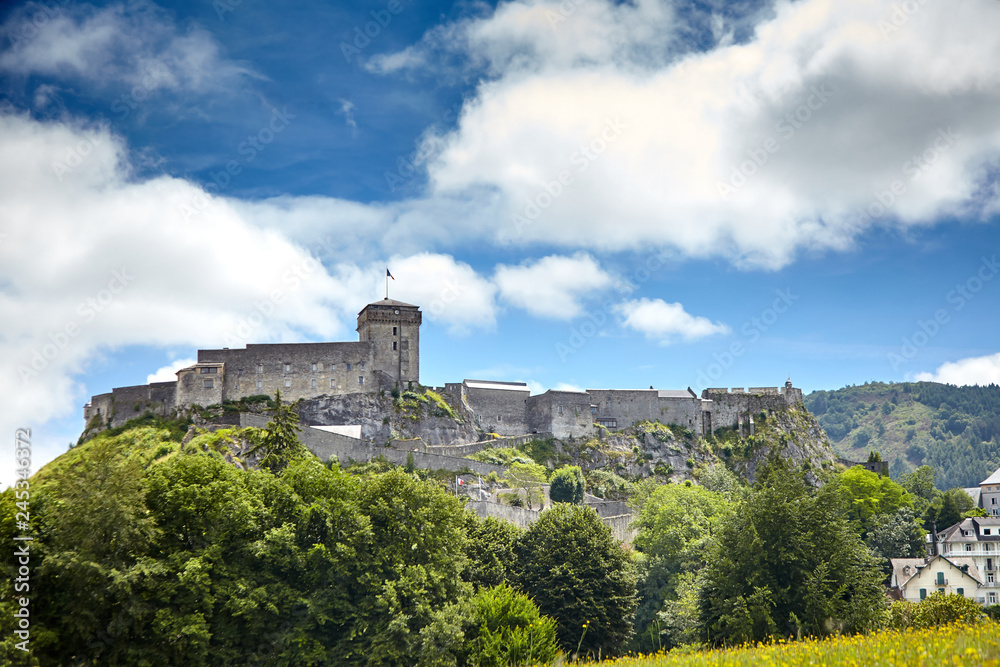Chateau Fort of Lourdes. Castle on a rock. Blue sky with white clouds. French city is located in southern France in the foothills of the Pyrenees mountains