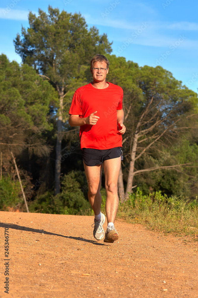 Young man running on the forest road at springtime Young man running on the forest road at springtime