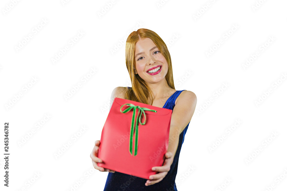 Portrait of a young red-haired girl in a blue evening dress with a gift in hand, holding a gift on her outstretched arms and smiling cutely looking into the camera
