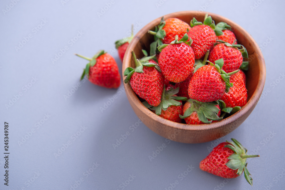 A bowl of beautiful and delicious strawberries isolated on a blue background, closeup, topview, copyspace. A bowl of beautiful and delicious strawberries isolated on a blue background, closeup, topview, copyspace.