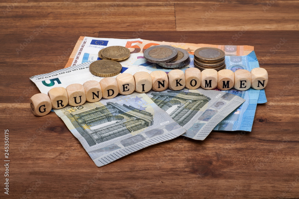 Die Euro Geldscheine und Münzen liegen auf dem Tisch mit dem Wort  Grundeinkommen Stock-Foto | Adobe Stock