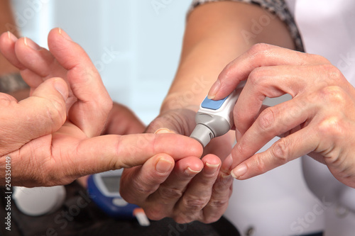 nurse instructs a diabetes test. She puts the needle on the pati  nt s finger