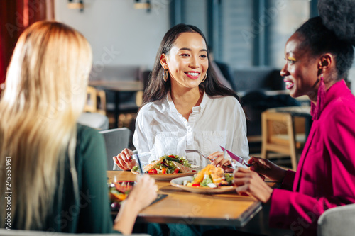 Three friends eating delicious salads in their favorite restaurant