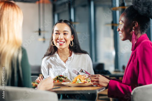 Three young businesswomen having informal meeting in restaurant