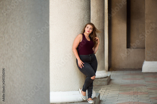 Young stylish woman walking on the city street in summer. Plus size model.