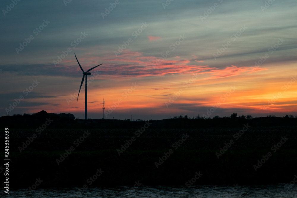 Silhouette of a windturbine and pastel colored clouds at sunset