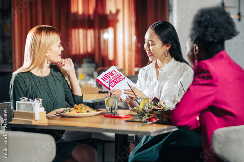 Three young single women reading book about finding husband