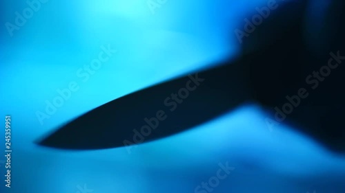 Sharp point of a knife reveals out of the darkness.
