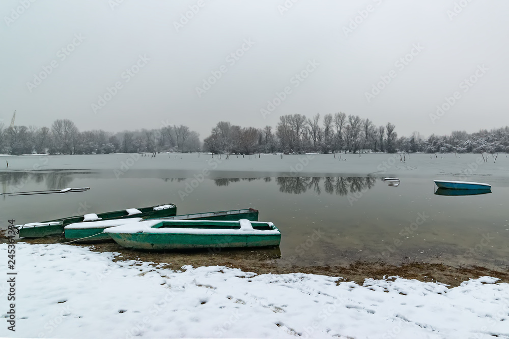 Naklejka premium Beautiful frozen river. A boats covered with snow.