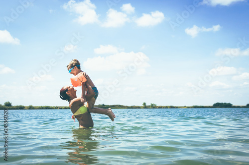 Cheerful mother and son having fun in water at the beach.