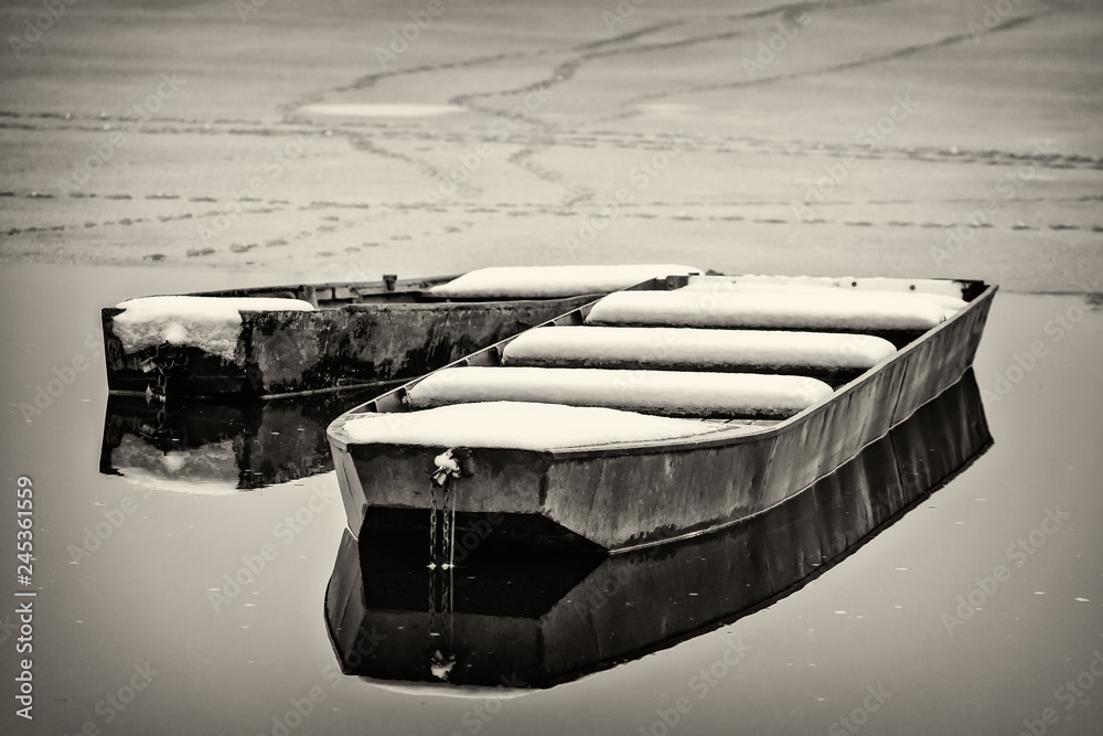 Naklejka premium Beautiful frozen river. A boats covered with snow.
