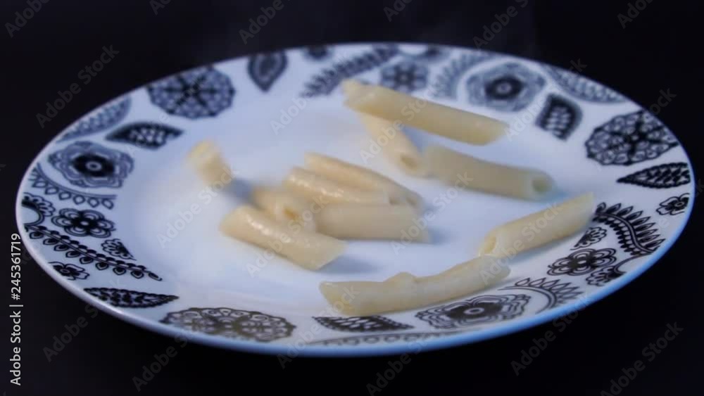 SLOW MOTION: Cooked tortiglioni fall into full plate Penne pasta with reach tomato sauce, a slice of cheese and some mint on the top