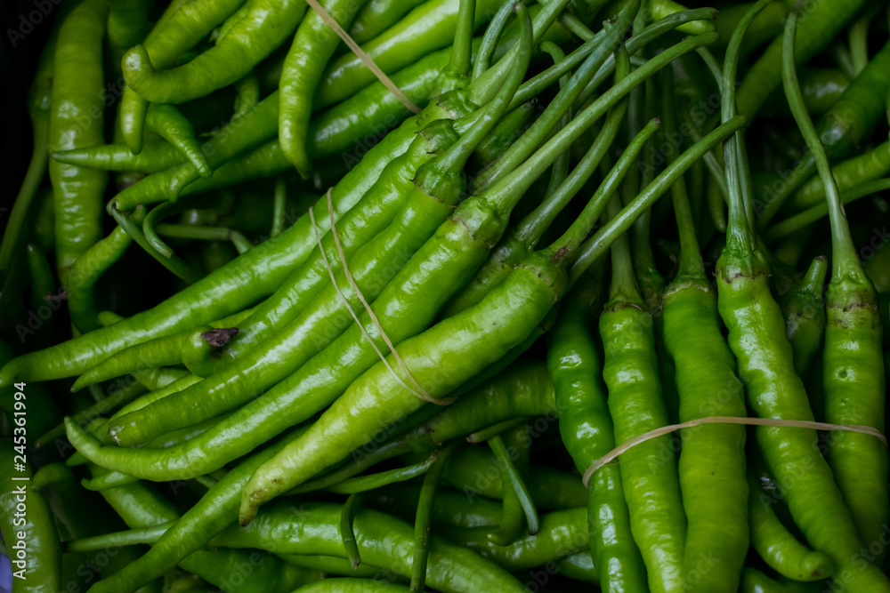 Close up view of a pile of green chilli pepper at a fresh market bazaar