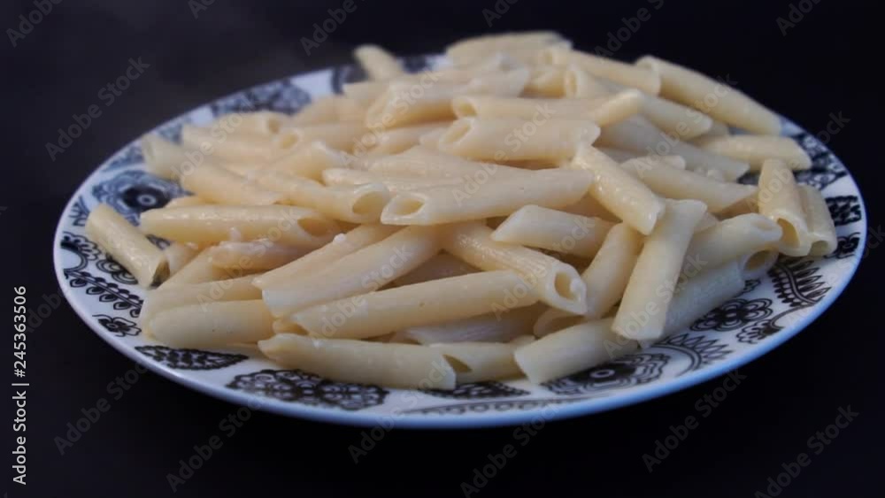 slow motion, Pouring marinara sauce onto spaghetti. Cooked penne pasta with butter and cheese and basil in vintage beautiful blue plate on wooden table. Isolated. Dish, mediterranean. slow motion, Pouring marinara sauce onto spaghetti. Cooked penne pasta with butter and cheese and basil in vintage beautiful blue plate on wooden table. Isolated. Dish, mediterranean.