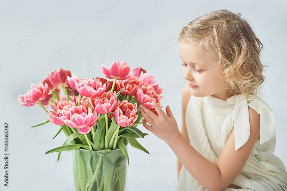 girl holding tulips in hands. Adorable smiling little girl holding flowers for her mom on mother's day.