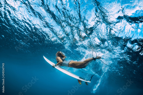 Photography Surfer woman with surfboard dive underwater with ocean wave.