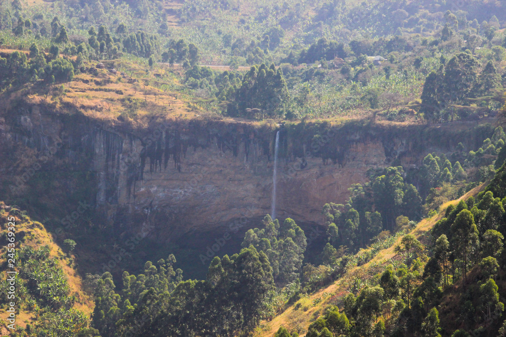 Obraz premium Tall and thin Sipi Falls flowing among rocks in Uganda