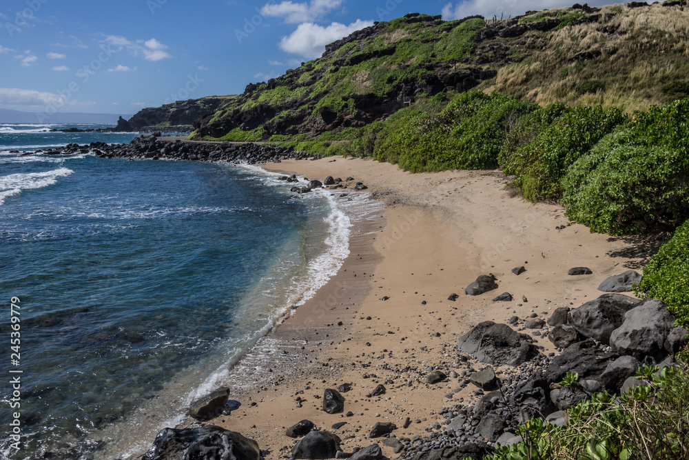 Sandy Cove in Hawaii:  A crescent shaped in lava rock cliffs gathers sand into a small beach in the Hawaiian Islands.