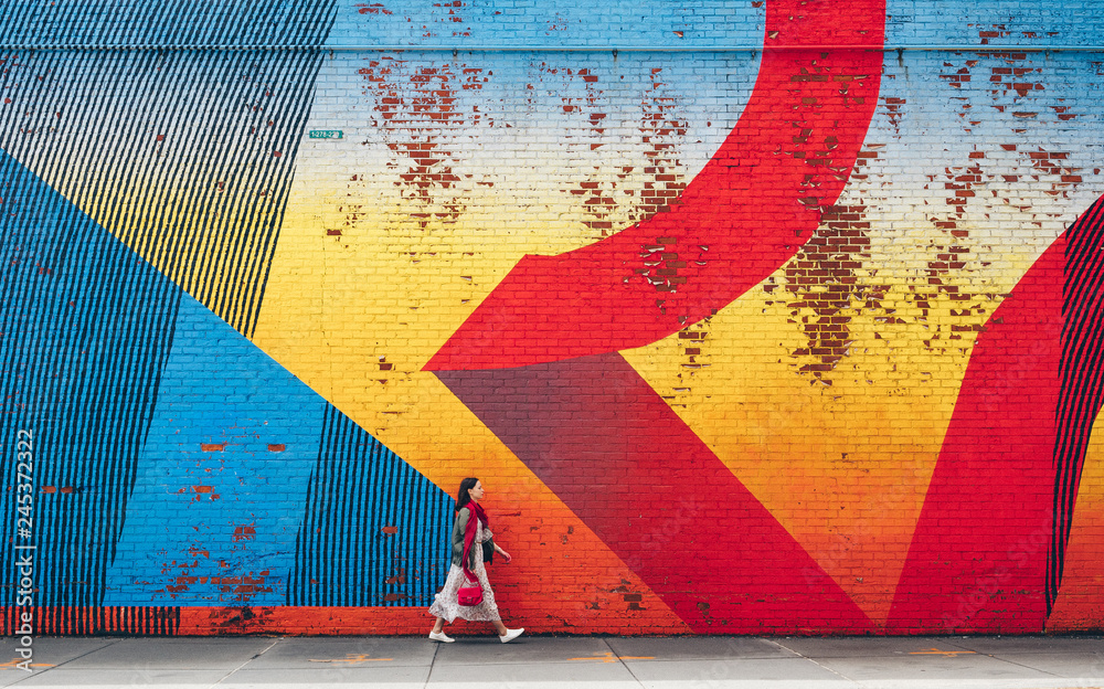 Obraz premium Młoda dziewczyna chodzi ścianą z graffiti