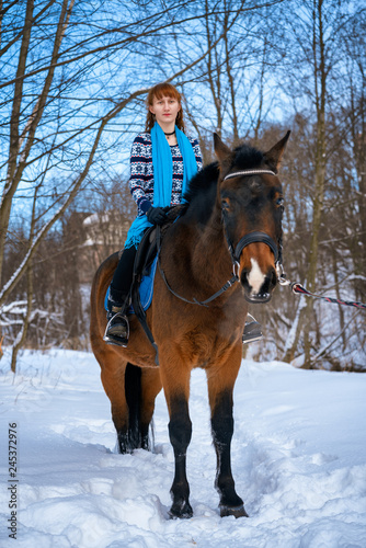 young woman with red hair on a horse in winter