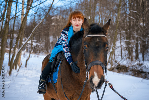 young woman with red hair on a horse in winter
