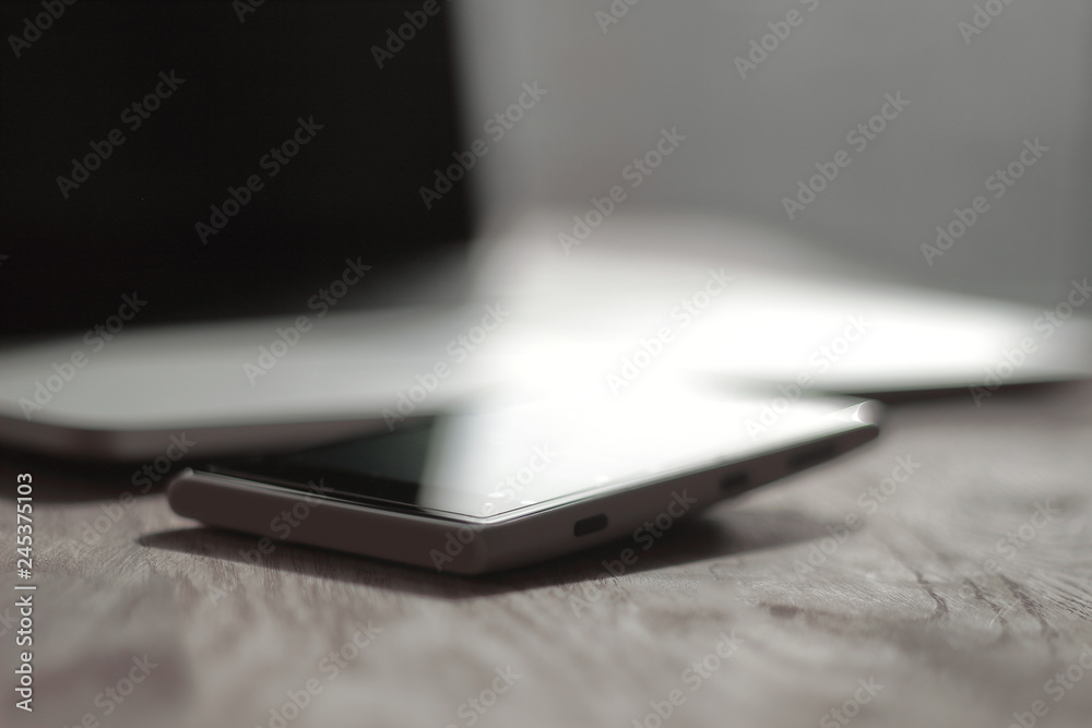 close up. blurred image of a mobile phone and laptop on the desktop close up. blurred image of a mobile phone and laptop on the desktop