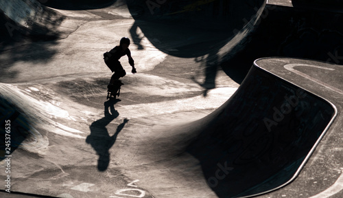 Skater als silhouette im Gegenlicht, im Hintergrund Skatepark photo