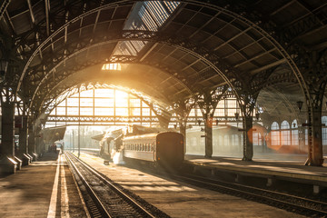 Fotobehang Trein Stoomtrein bij avondzon op perron  © aapsky