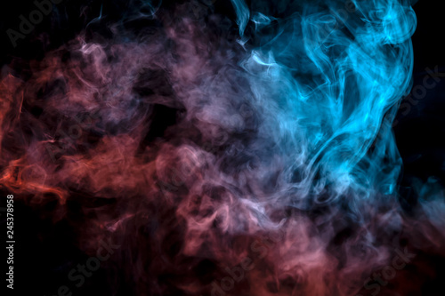 The exhaled column of vapor illuminated with blue and pink light evaporates in thin streams against a black background as it clumps into smoke.