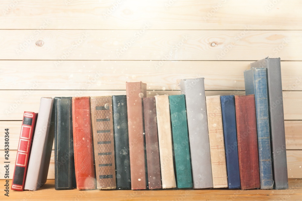 Naklejka premium Ancient books in a row on wooden background
