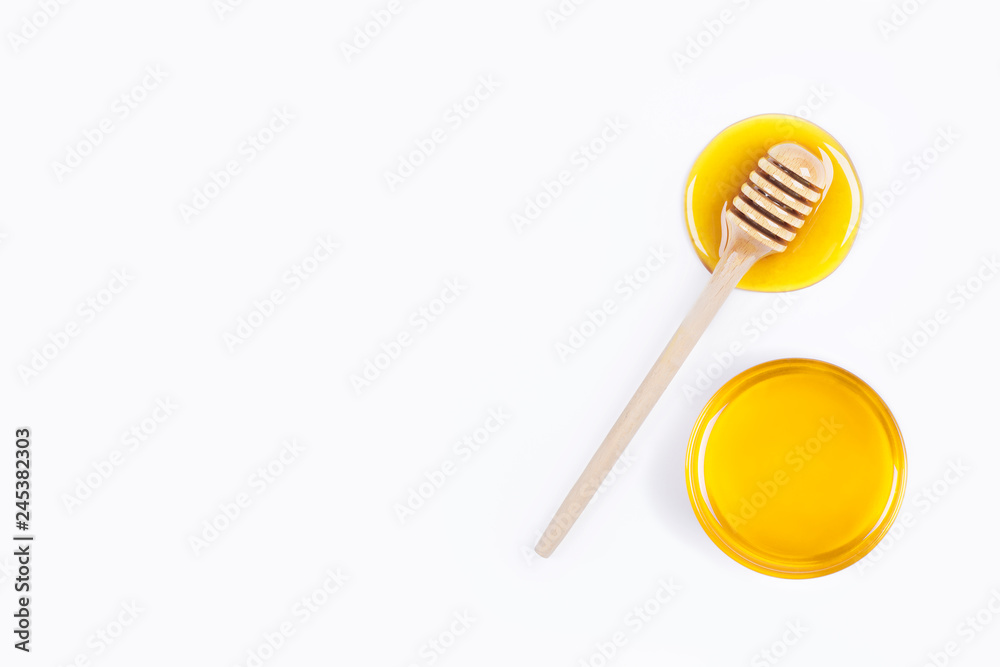 Honey dipper in honey and a jar of honey isolated on light grey background Honey dipper in honey and a jar of honey isolated on light grey background