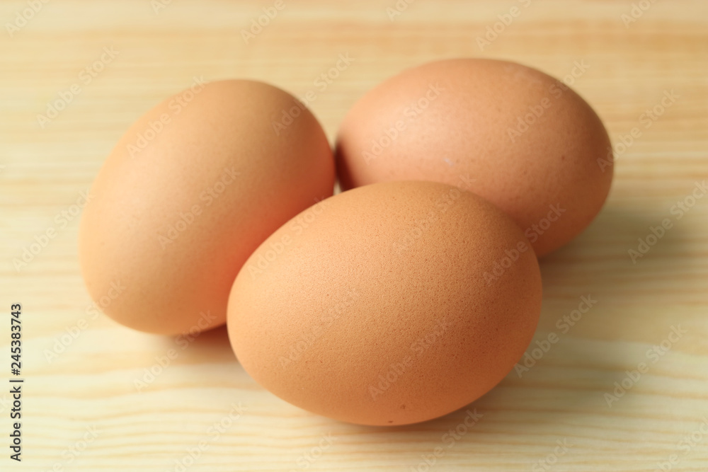 Three uncooked fresh chicken eggs isolated on the wooden table Three uncooked fresh chicken eggs isolated on the wooden table