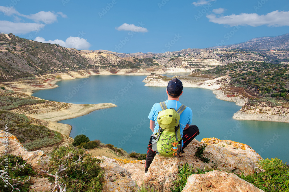 tourist with backpack looks at a beautiful reservoir from a viewing platform in Cyprus